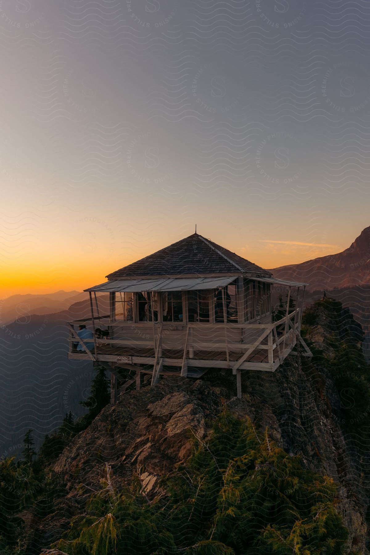 Man with a dog on the balcony of a building on top of a mountain peak