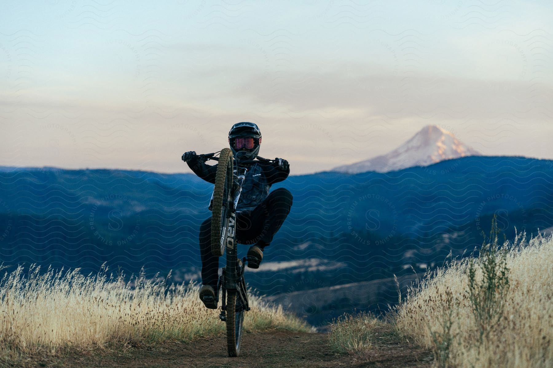 A person is doing a wheelie maneuver on a mountain bike.