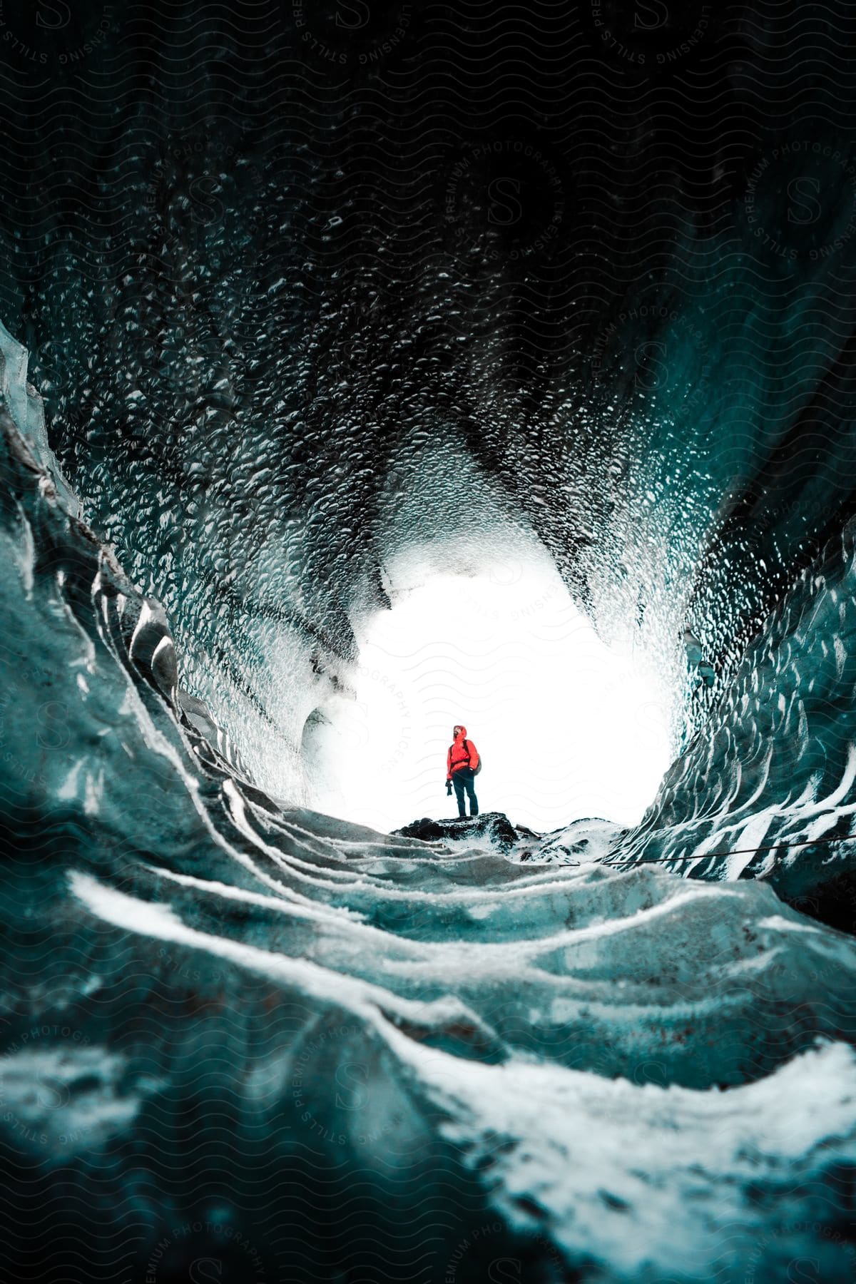 A man standing at the end of an ice tunnel on a sunny day in the arctic.