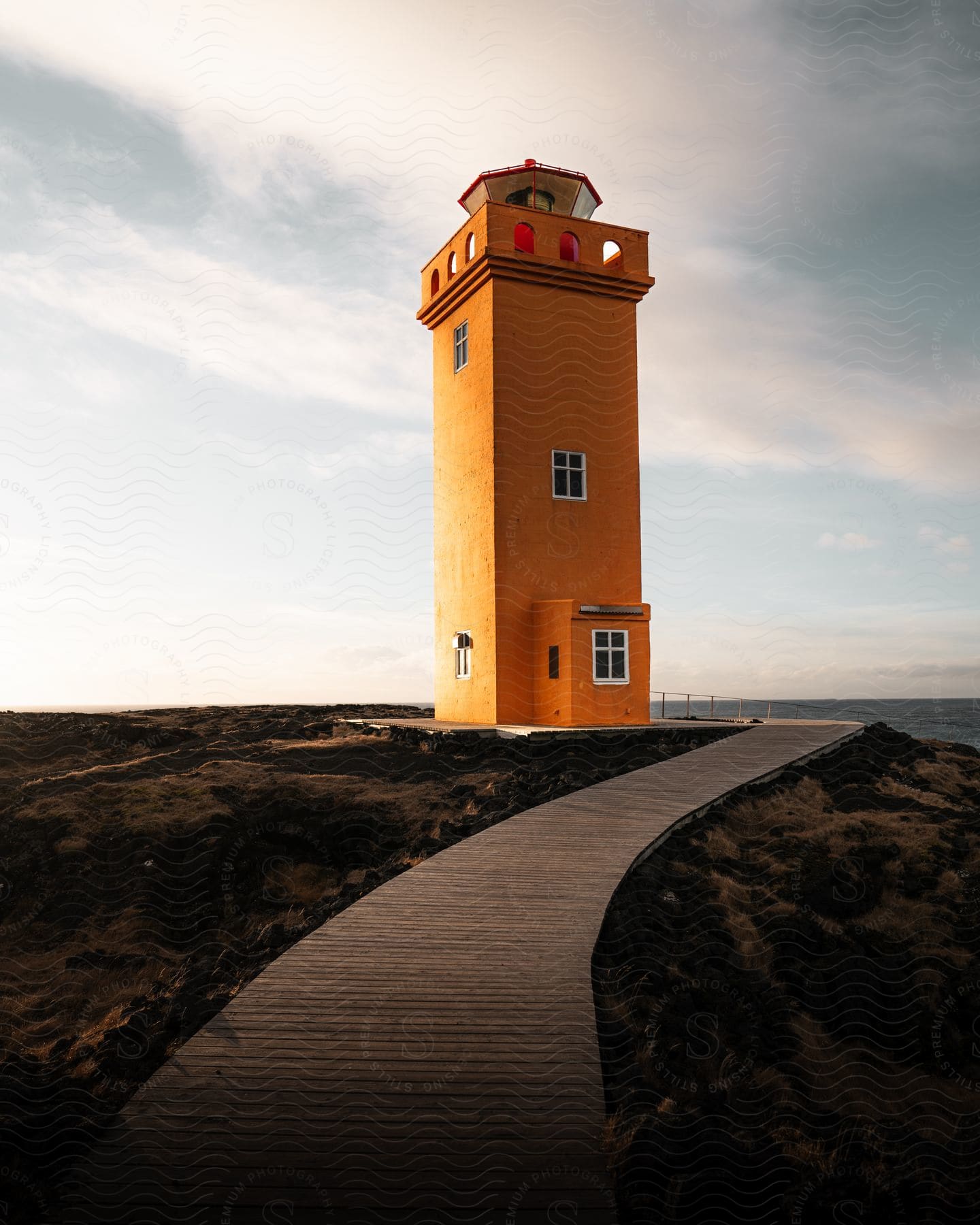 Walkway leading to the orange Svortuloft lighthouse tower along the coast in Iceland