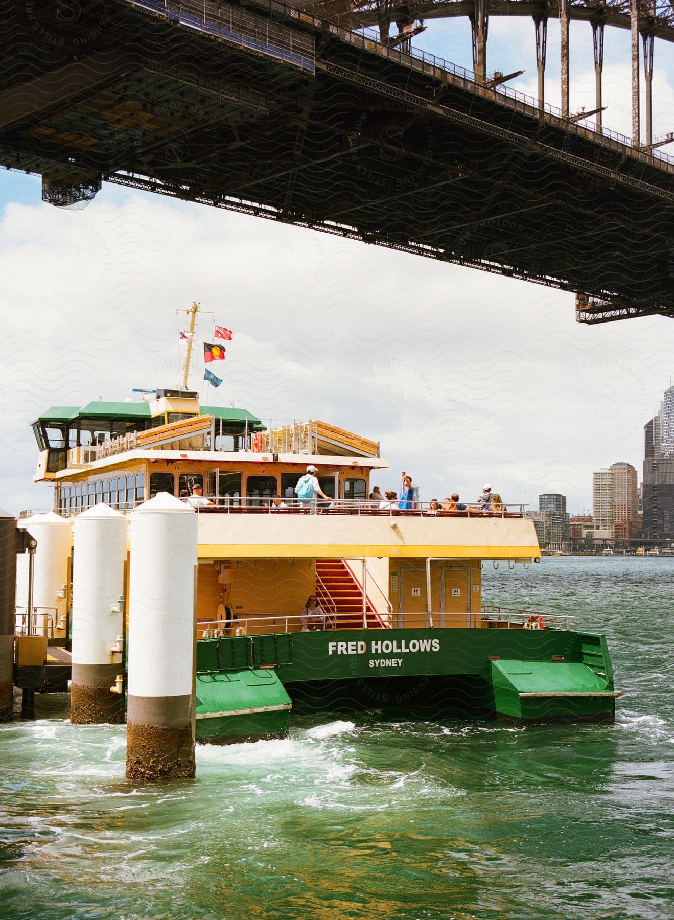 Sydney Ferries boat with tourists passing over a bridge.