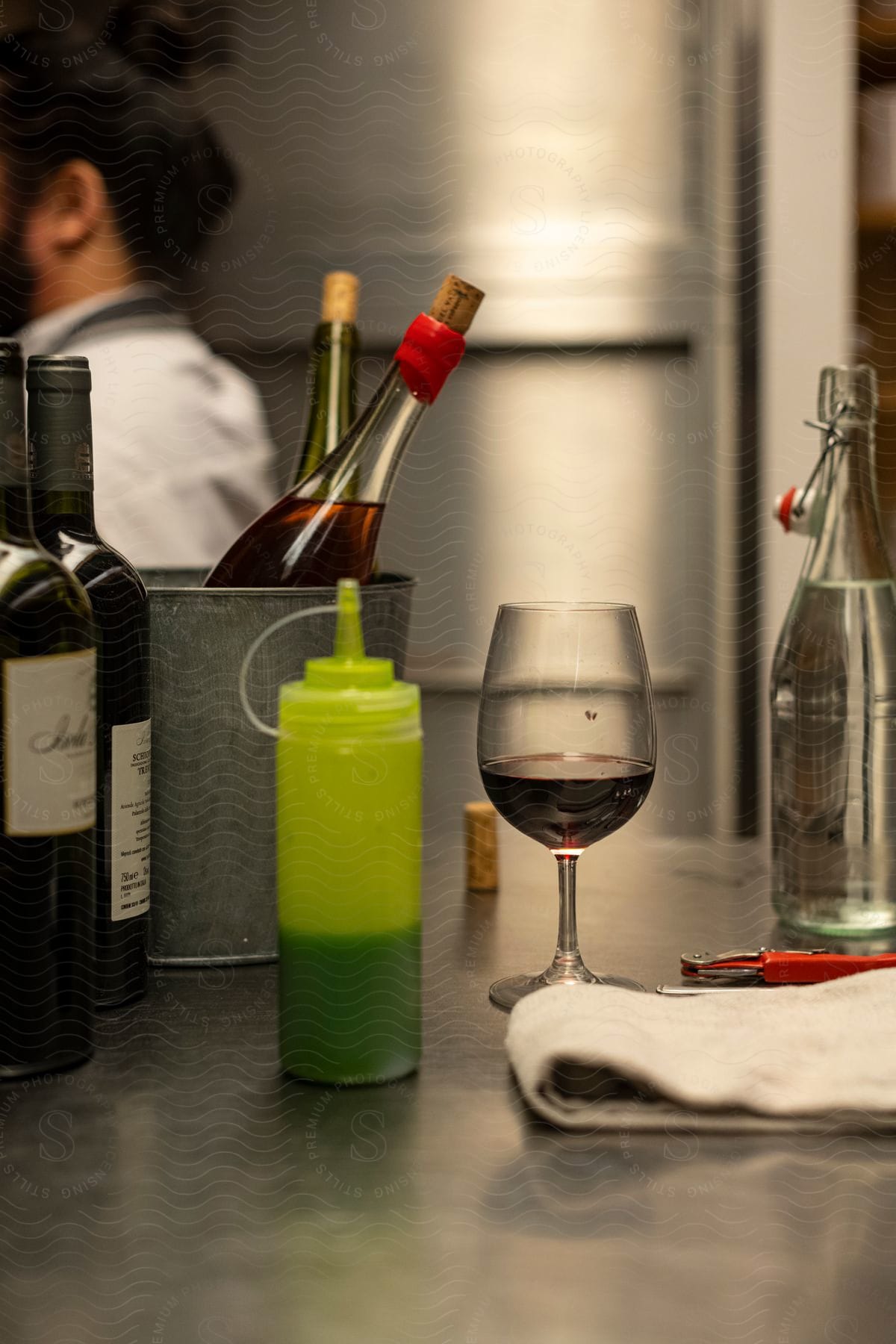 Wine bottles and a glass on a metal countertop