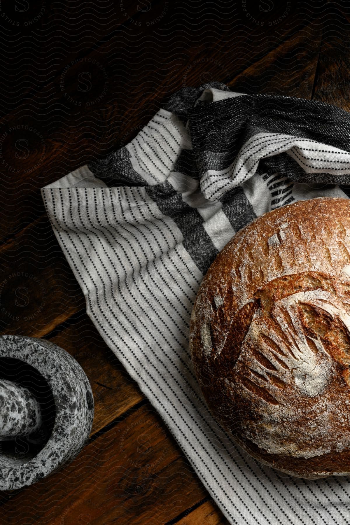 Rustic bread on a striped towel next to a mortar and pestle.