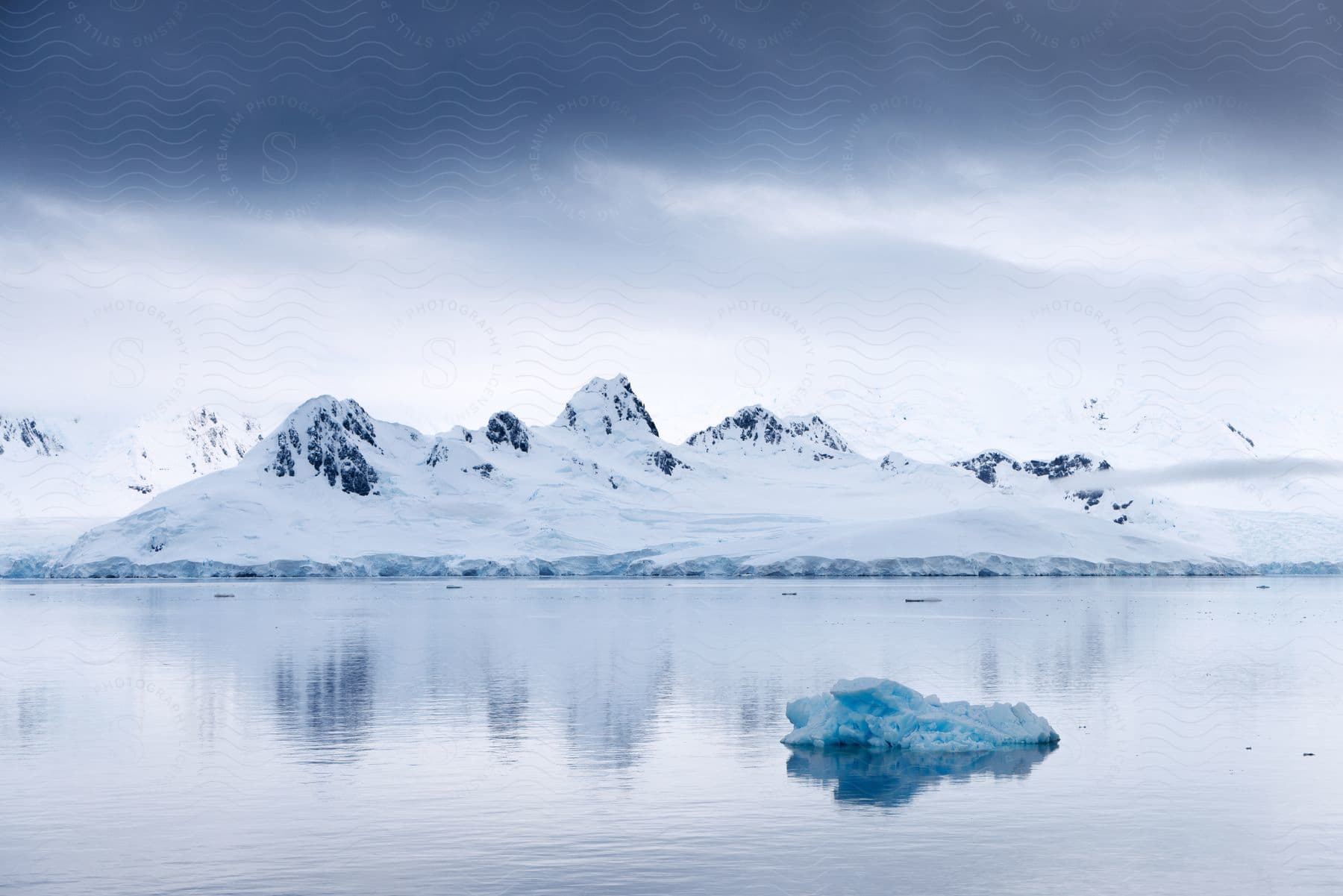 In the Arctic, an island with rocks is covered in snow and ice during the daytime.