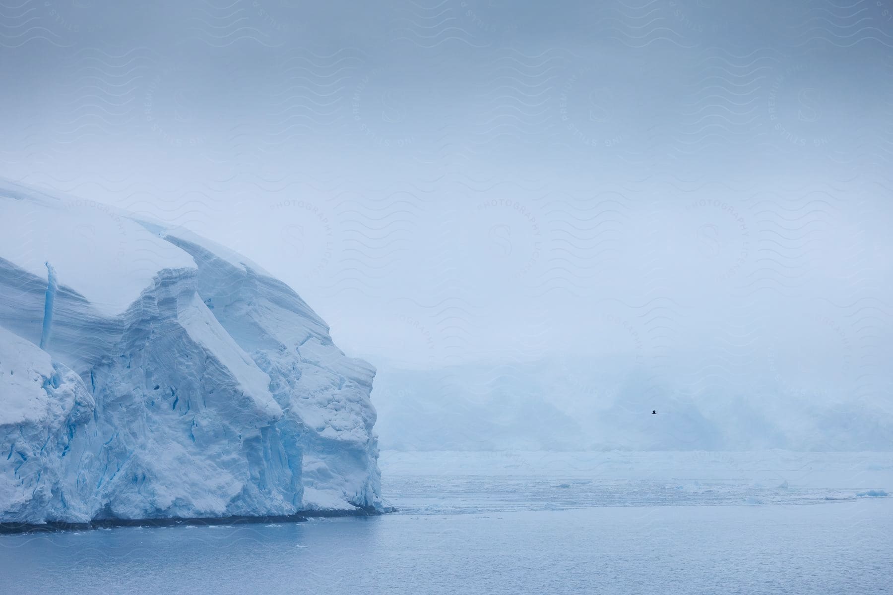 Large ice formations along the edge of the sea under a cloudy sky.