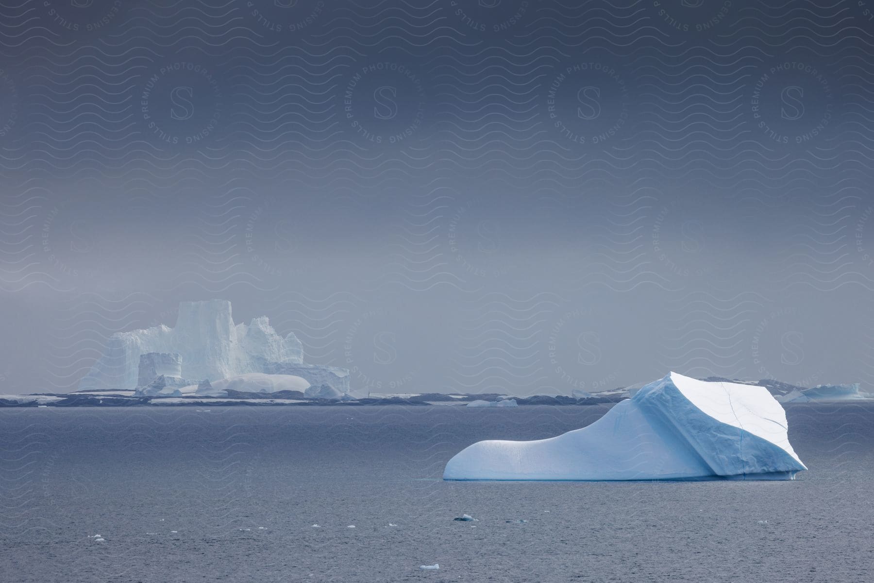 Tranquil seascape with icebergs under gray clouds and calm sea with scattered ice