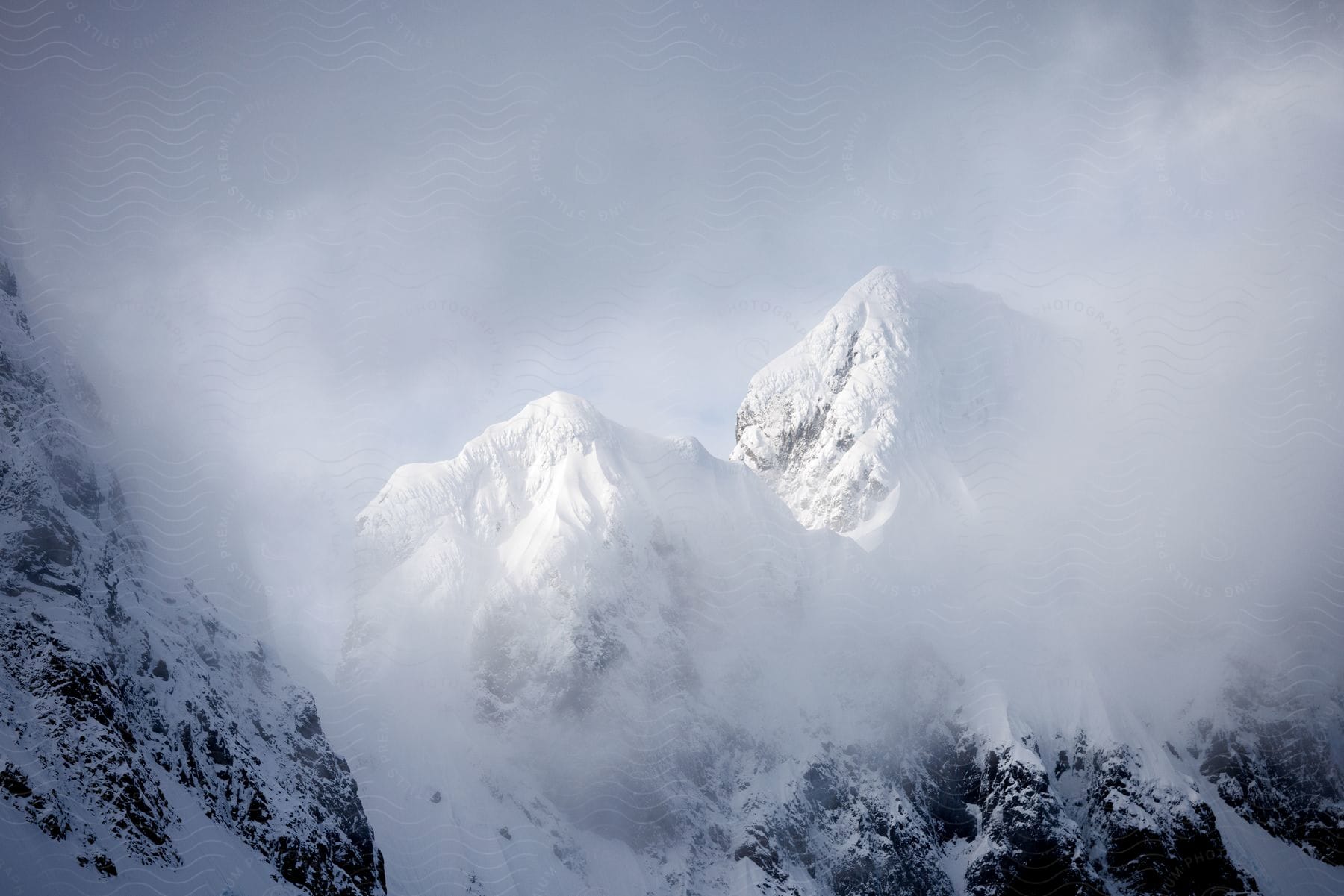 A majestic snow-capped mountain emerges through the clouds, creating an impressive and dramatic scene.