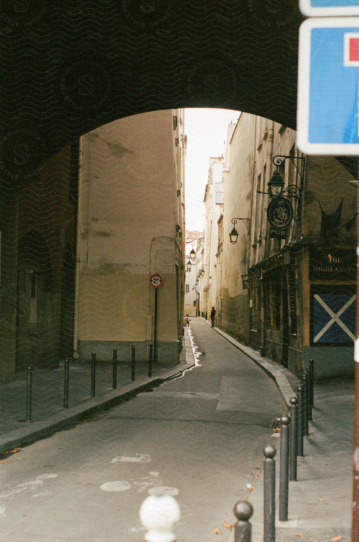 A narrow alleyway framed by an arch with buildings on either side