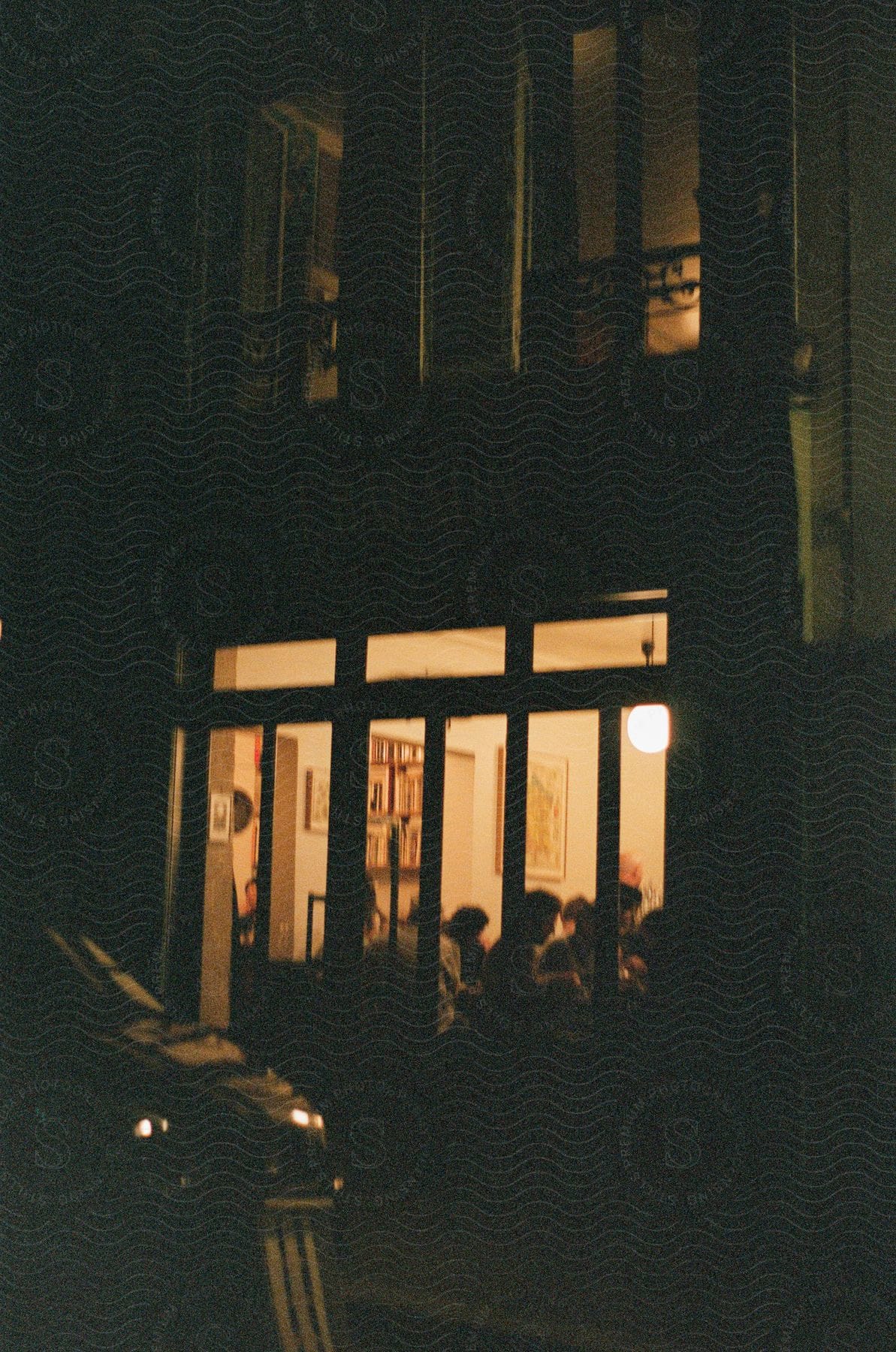 A dimly lit café in the city with patrons inside at night