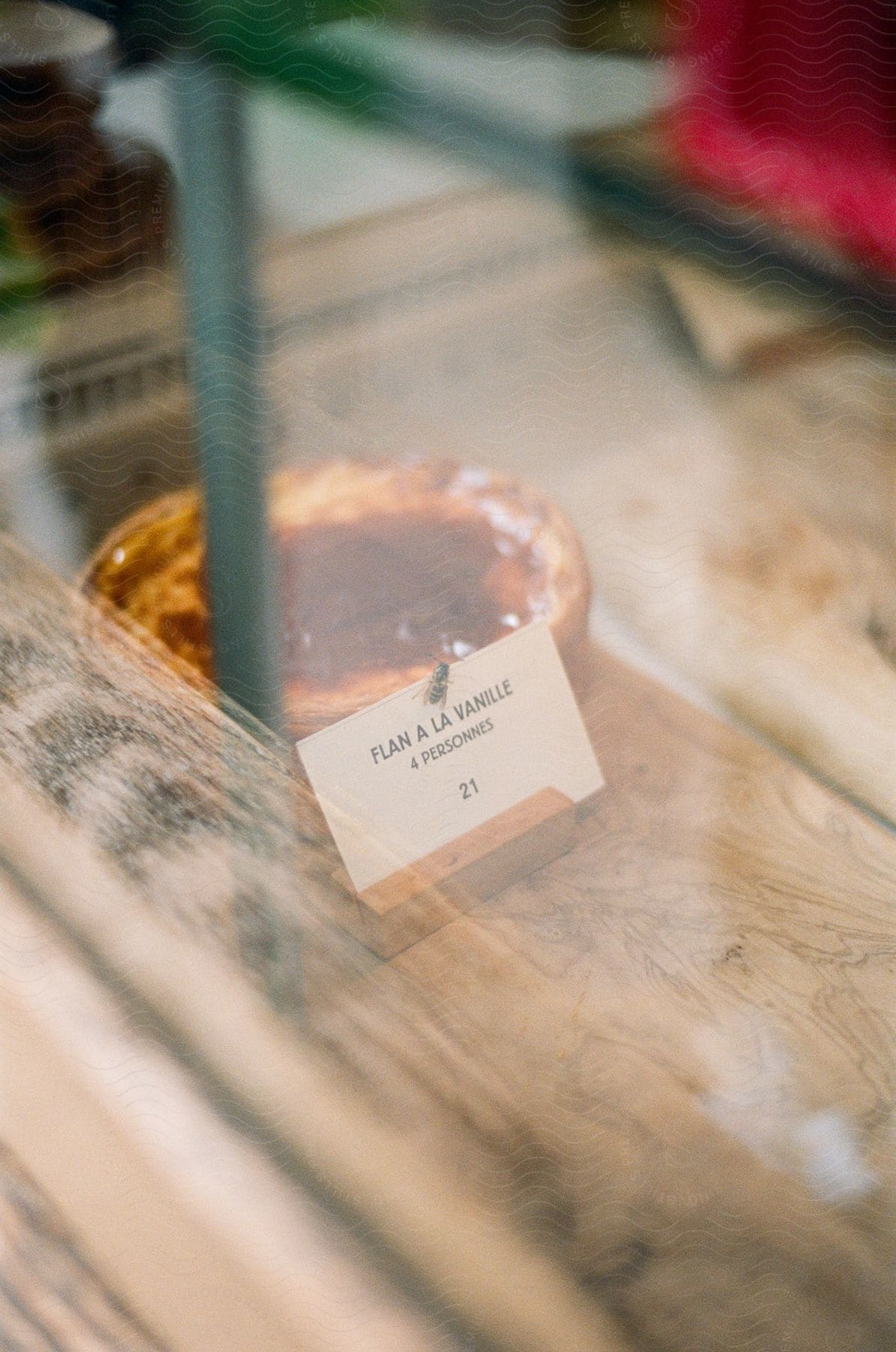 A bakery product is displayed in a glass shelf with the written inscription "FLAN A LA VANILLE".