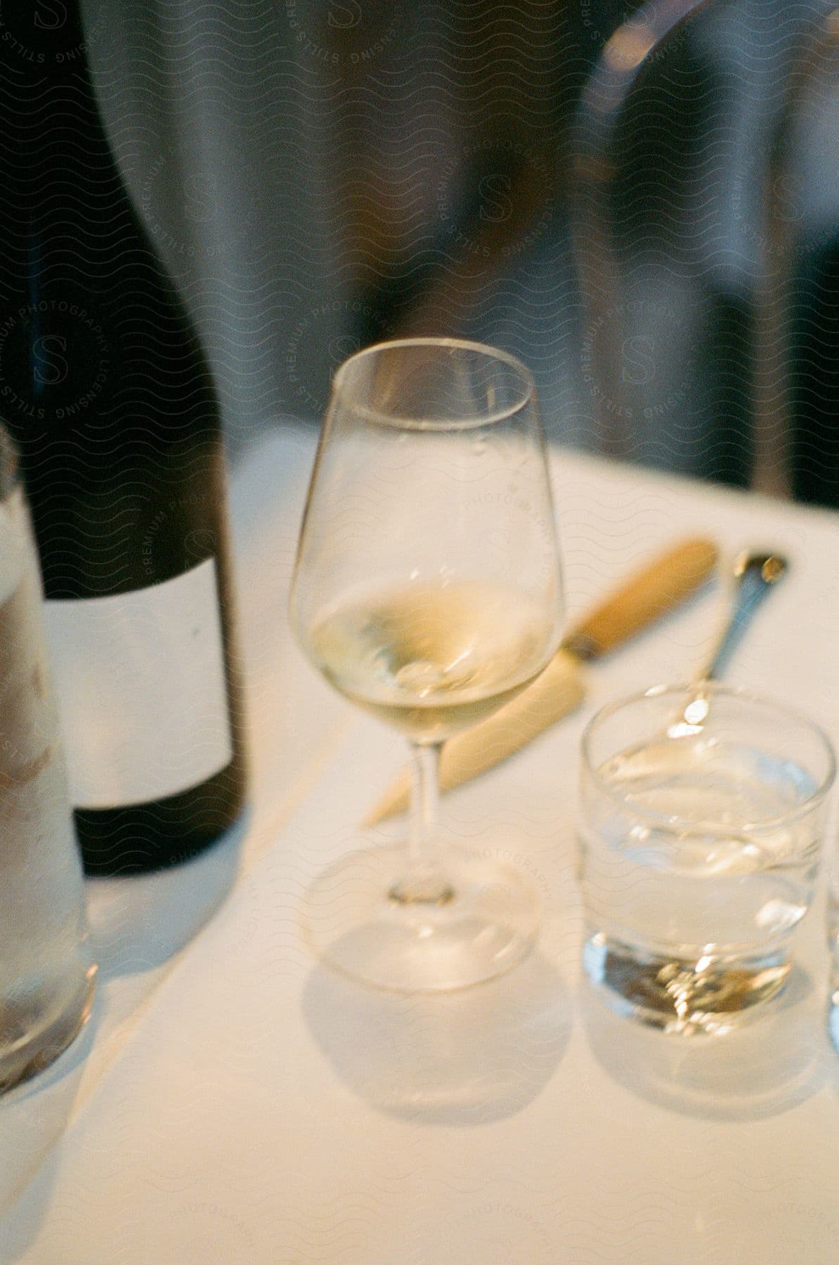 A wine bottle and two glasses are on a table beside a knife