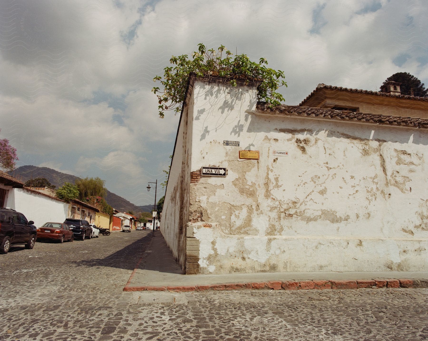 Automobiles parked on a neighborhood street and a wall