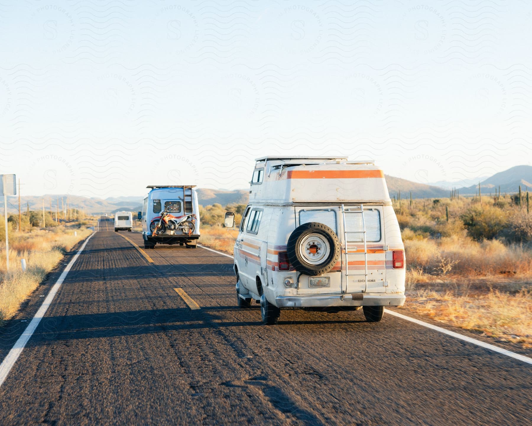 Travel vans traveling along a paved street in the middle of a desert biome environment