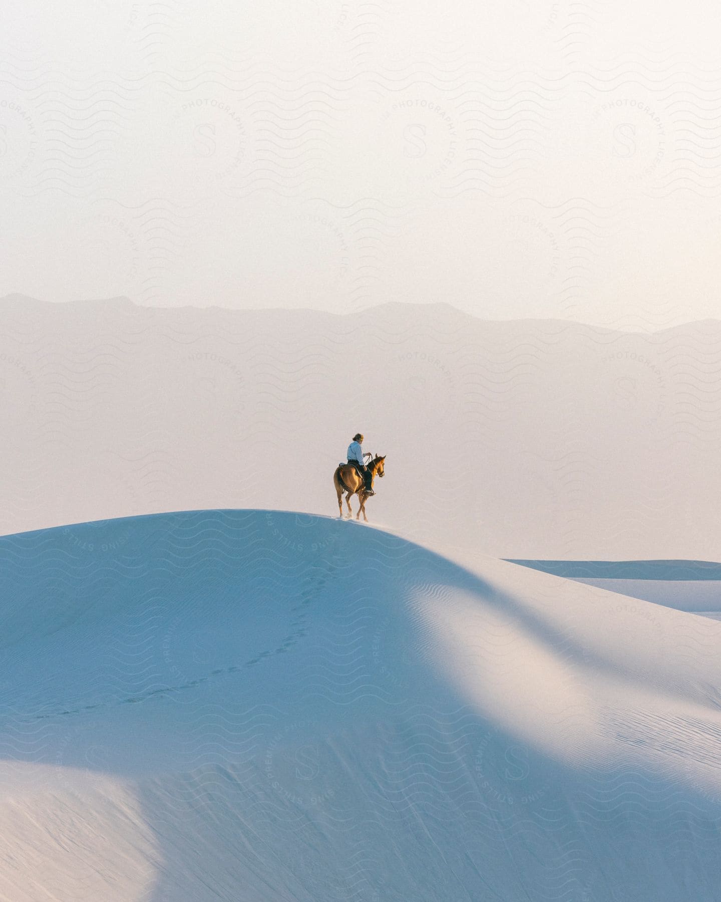 A person riding a horse over sand dunes in a desert region