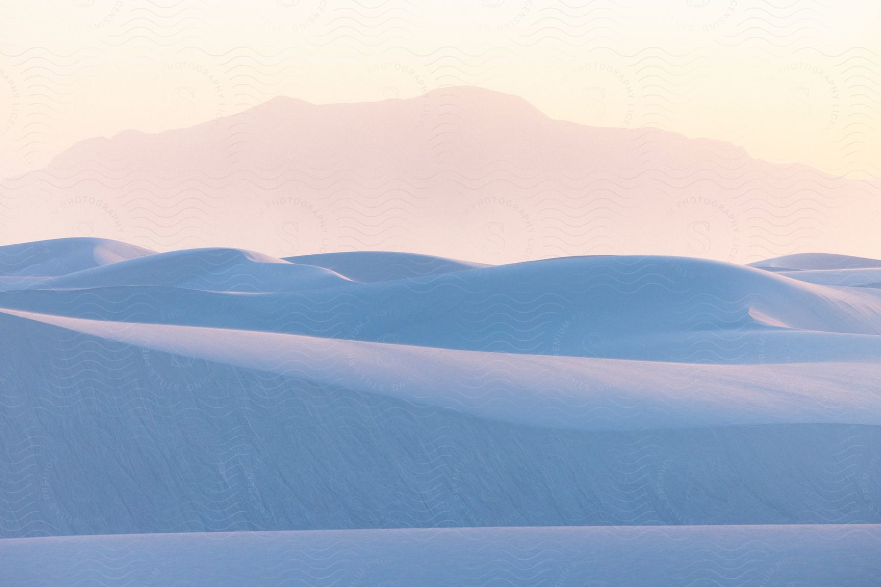 Several sand dunes in a desert region with partly white sky