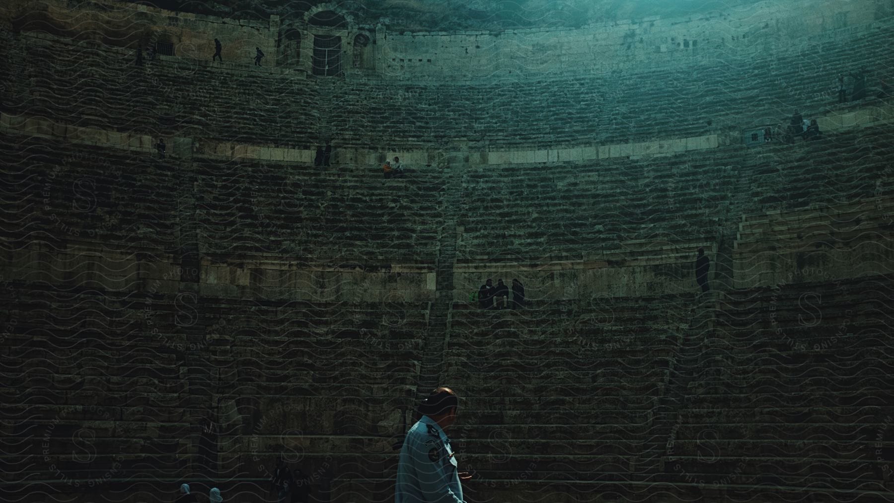 Interior of an arena with ancient ruins and tourists.