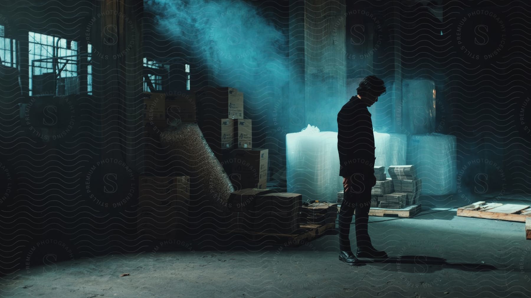 Man in black suit and shoes inside a warehouse with boxes