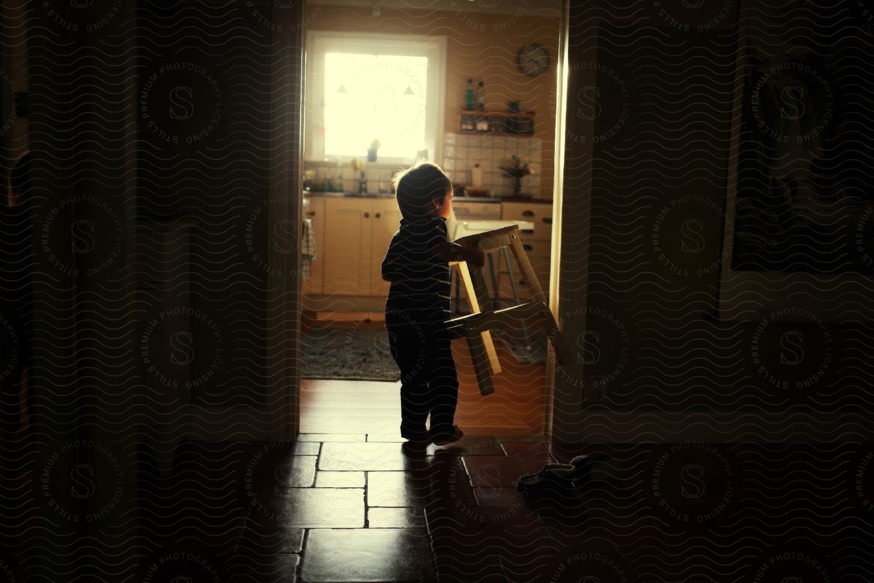 A child carrying a stool in a house