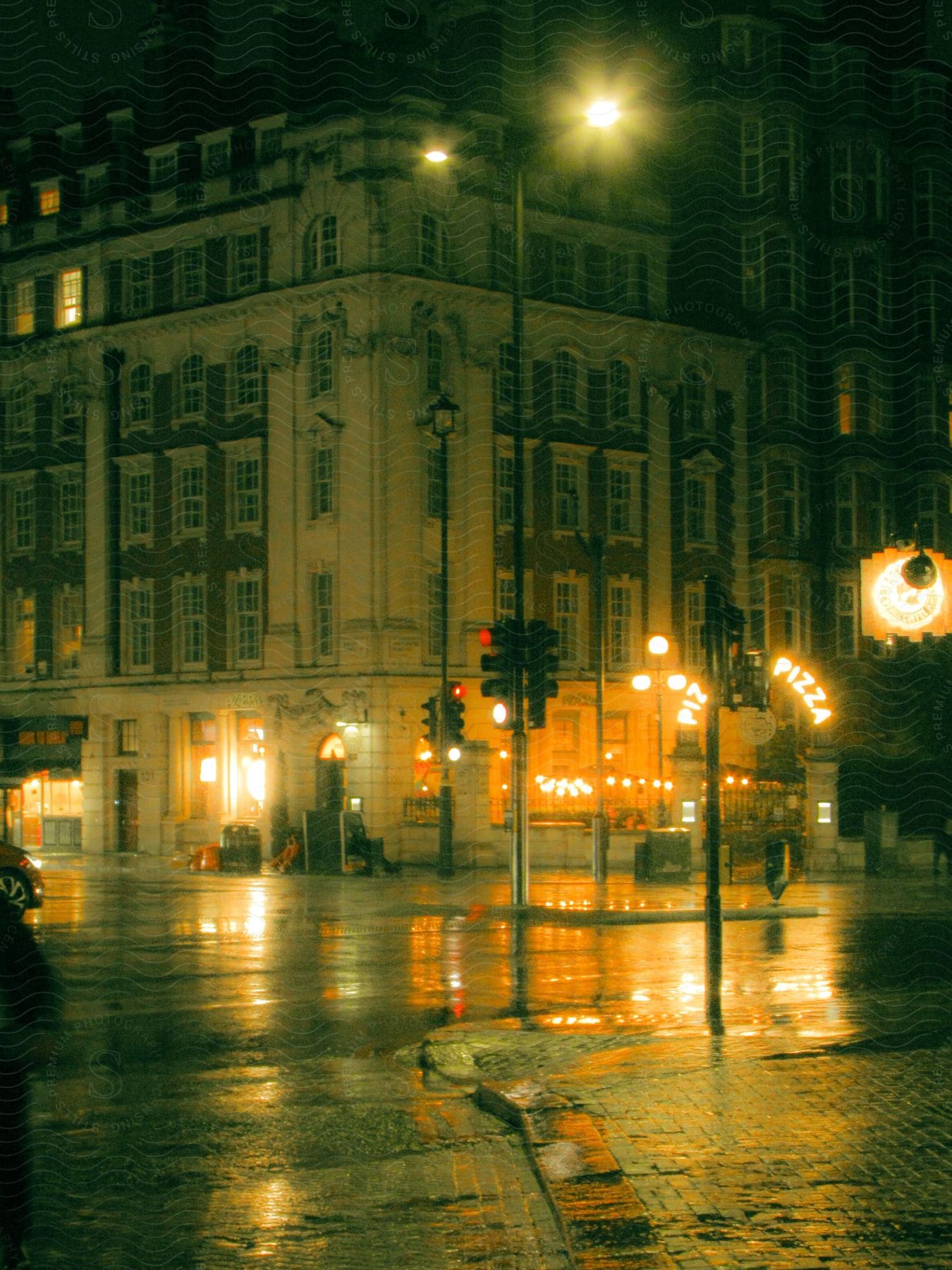 Lights shine on a downtown street and reflect on the rain in the darkness