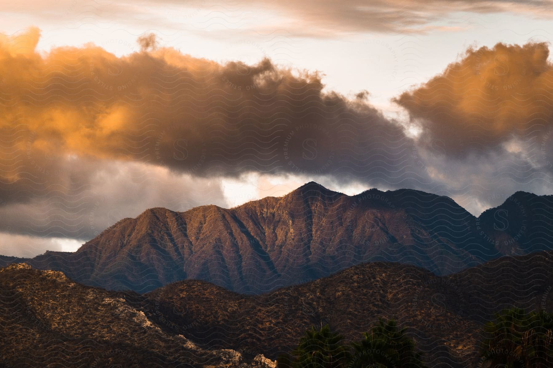 Sunlight shines upon dark clouds over a mountain range