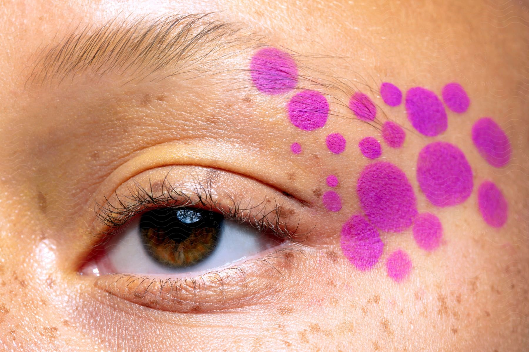 Purple dot makeup next to a woman's eye