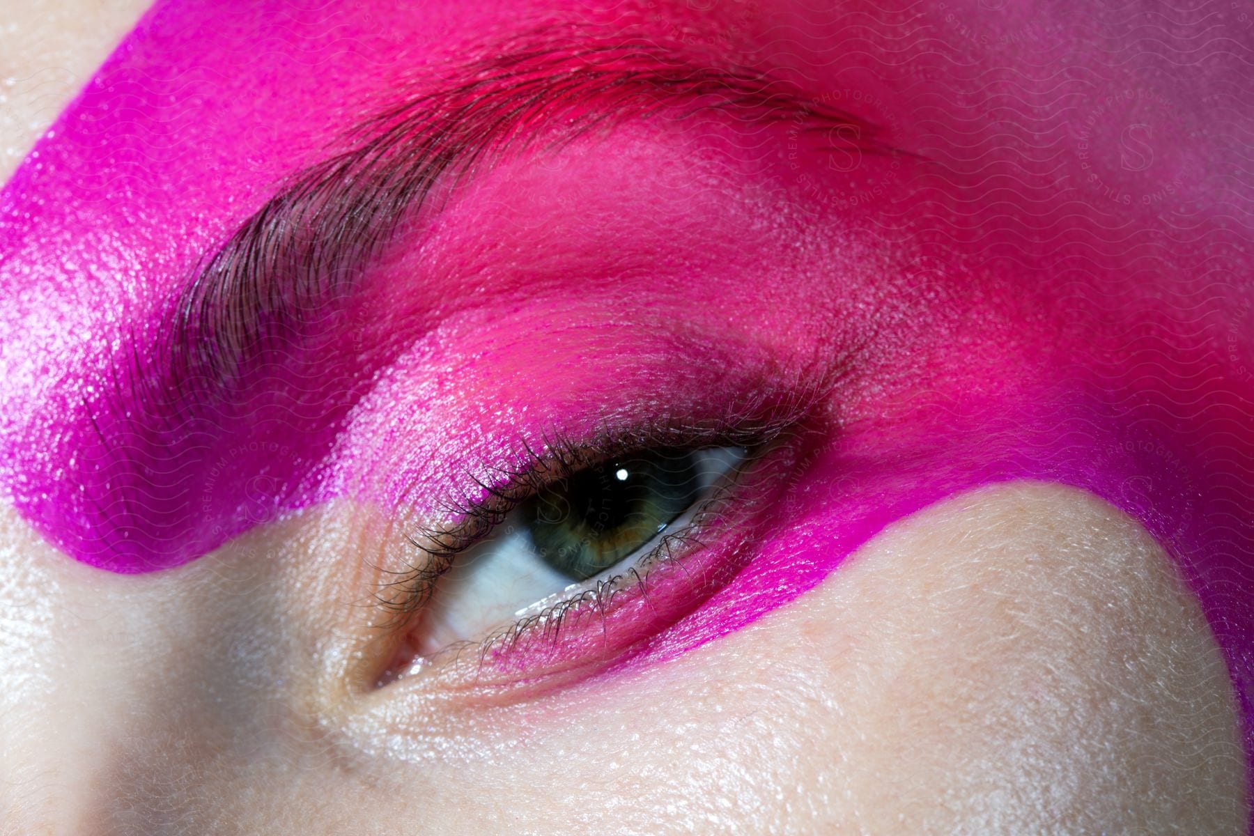 Close-up of an eye with vibrant pink eyeshadow covering the eyelid and brow area.