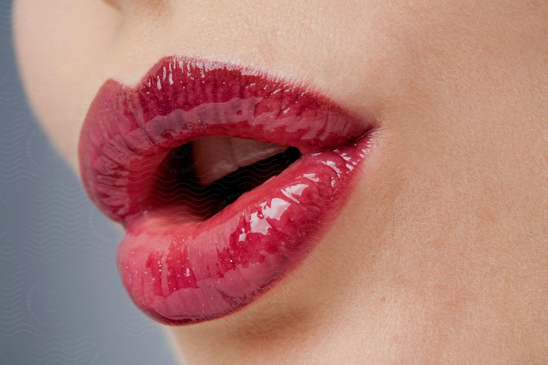 The lips of a person who is using bright red cosmetics and has their mouth partially open