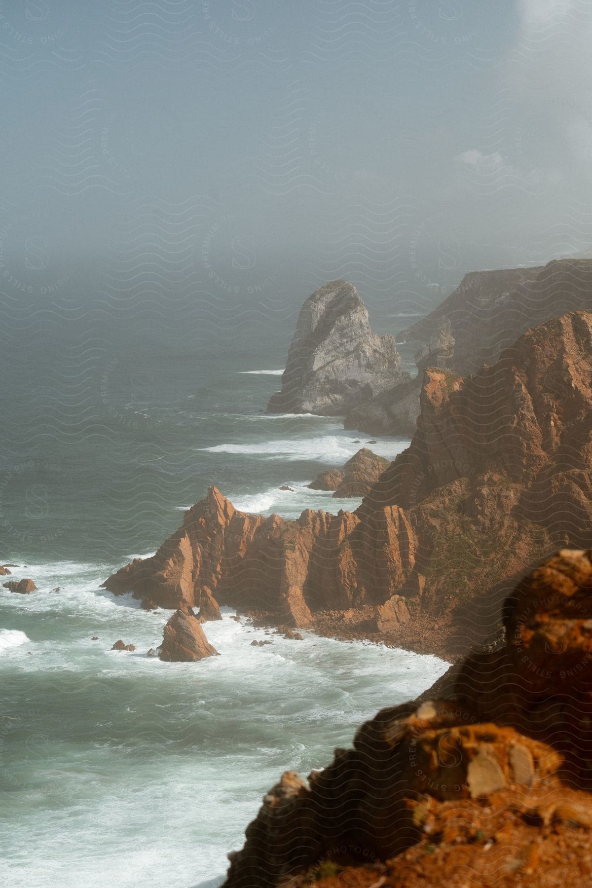 A dramatic and mysterious landscape with imposing cliffs and turbulent ocean waves.