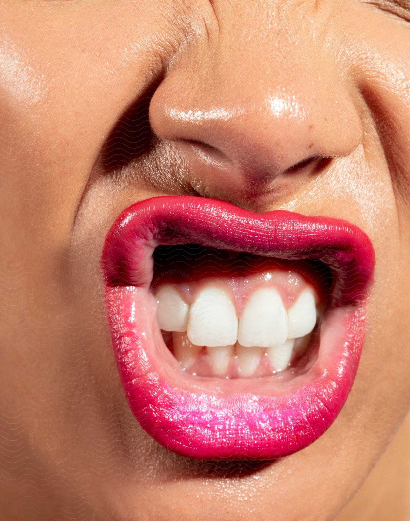 A close-up of a woman’s mouth wearing bright pink lipstick showing her teeth