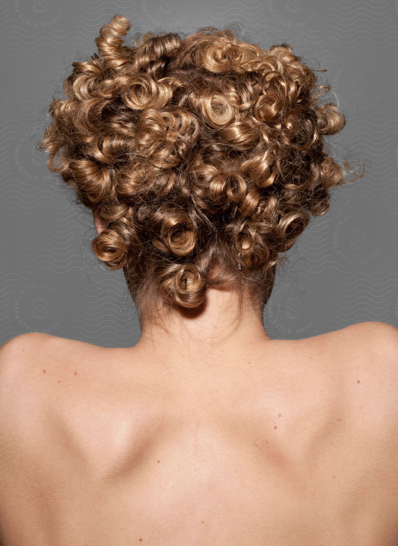 Woman from the back with contracted shoulder blades and curly blond hair