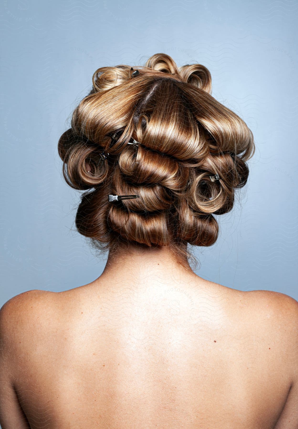 A woman's bare back with hair rollers in her hair