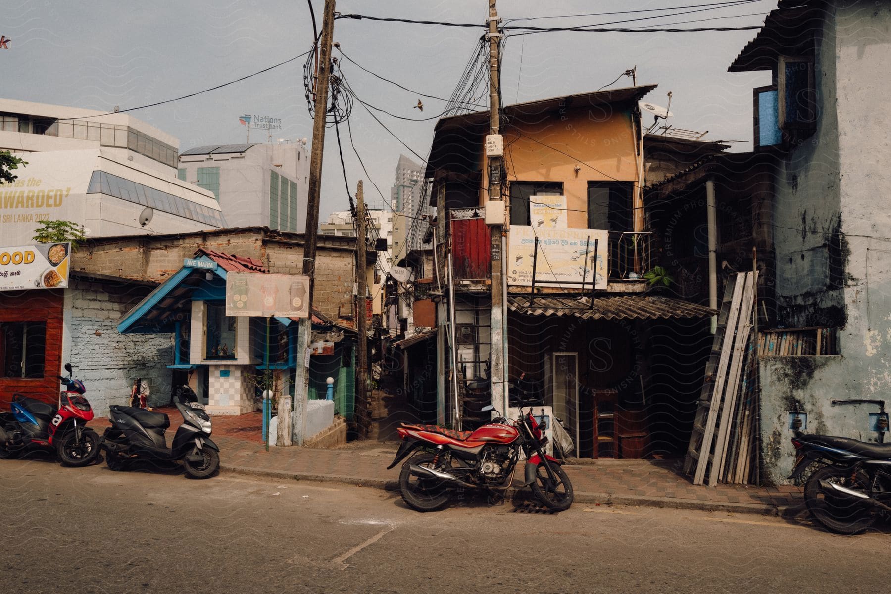 Several motorcycles are parked in front of weathered buildings in the suburban area