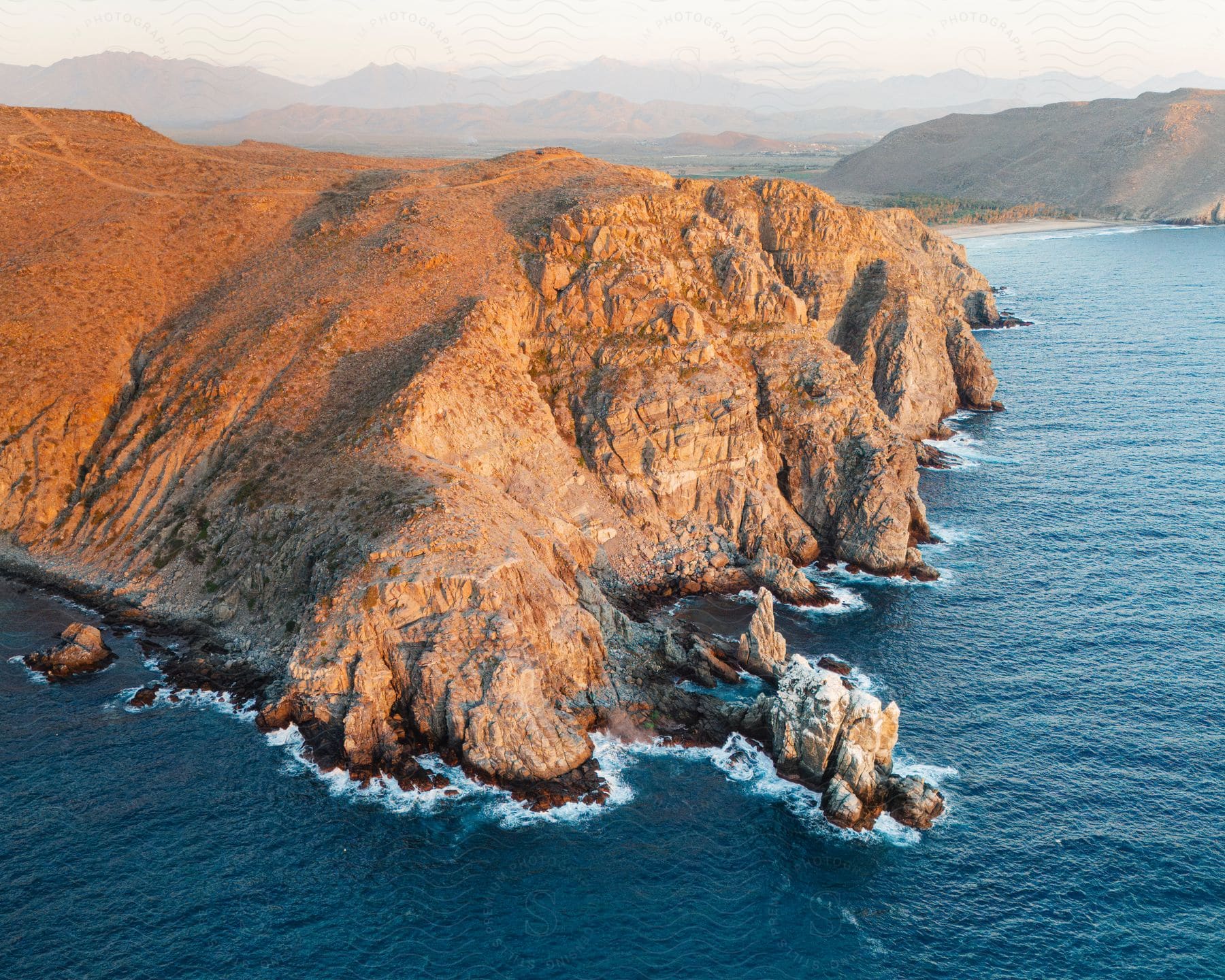 Aerial view of a rugged coastline with steep cliffs and a clear blue sea.