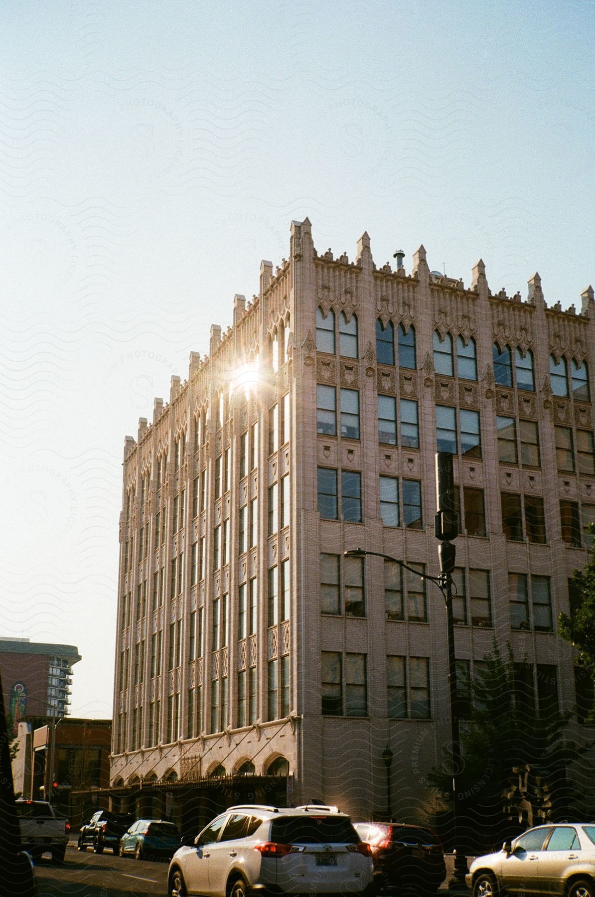 Traffic moves on a street passing a building with gothic spires and arches