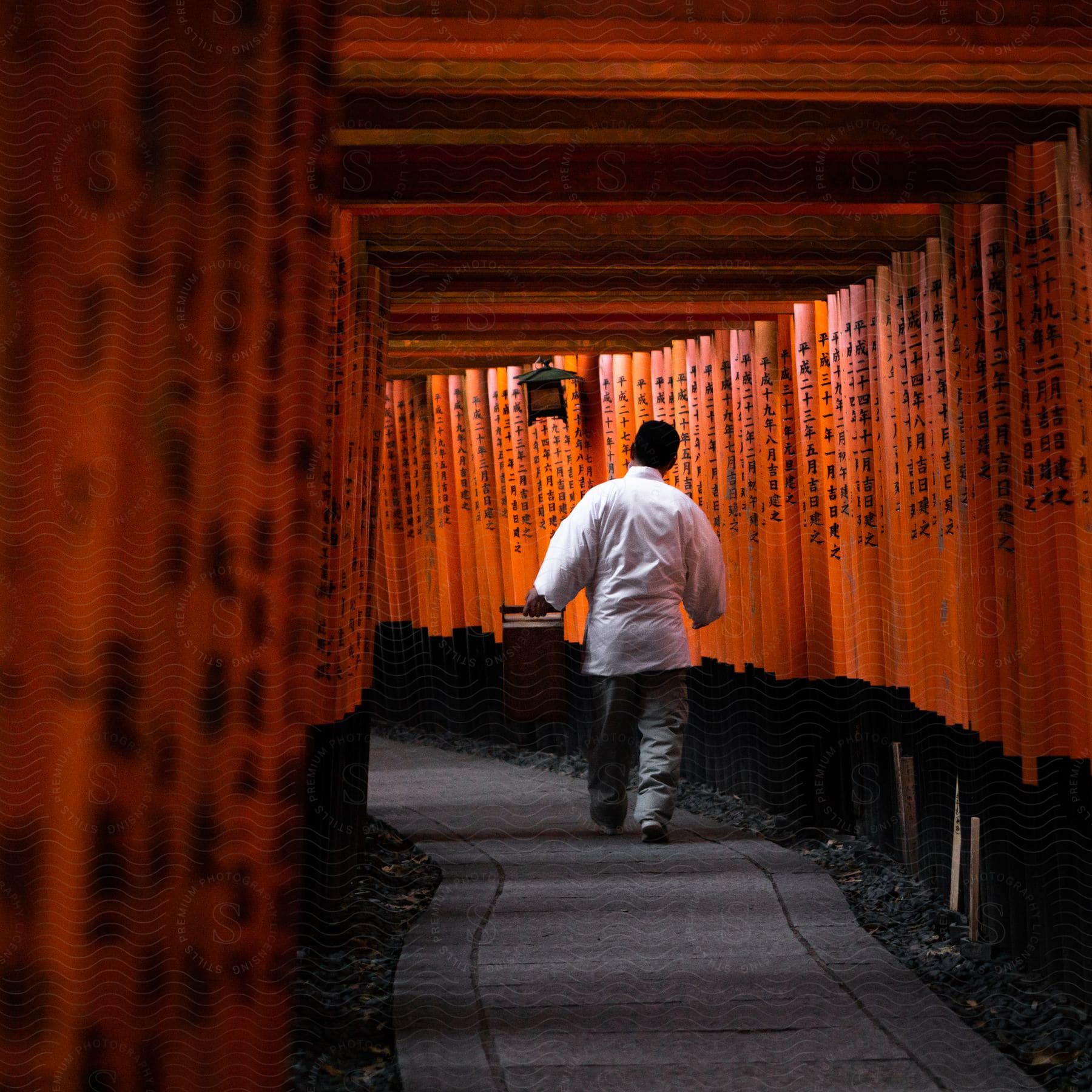 Man carrying a large food delivery container walks through a corridor formed of narrow posts.
