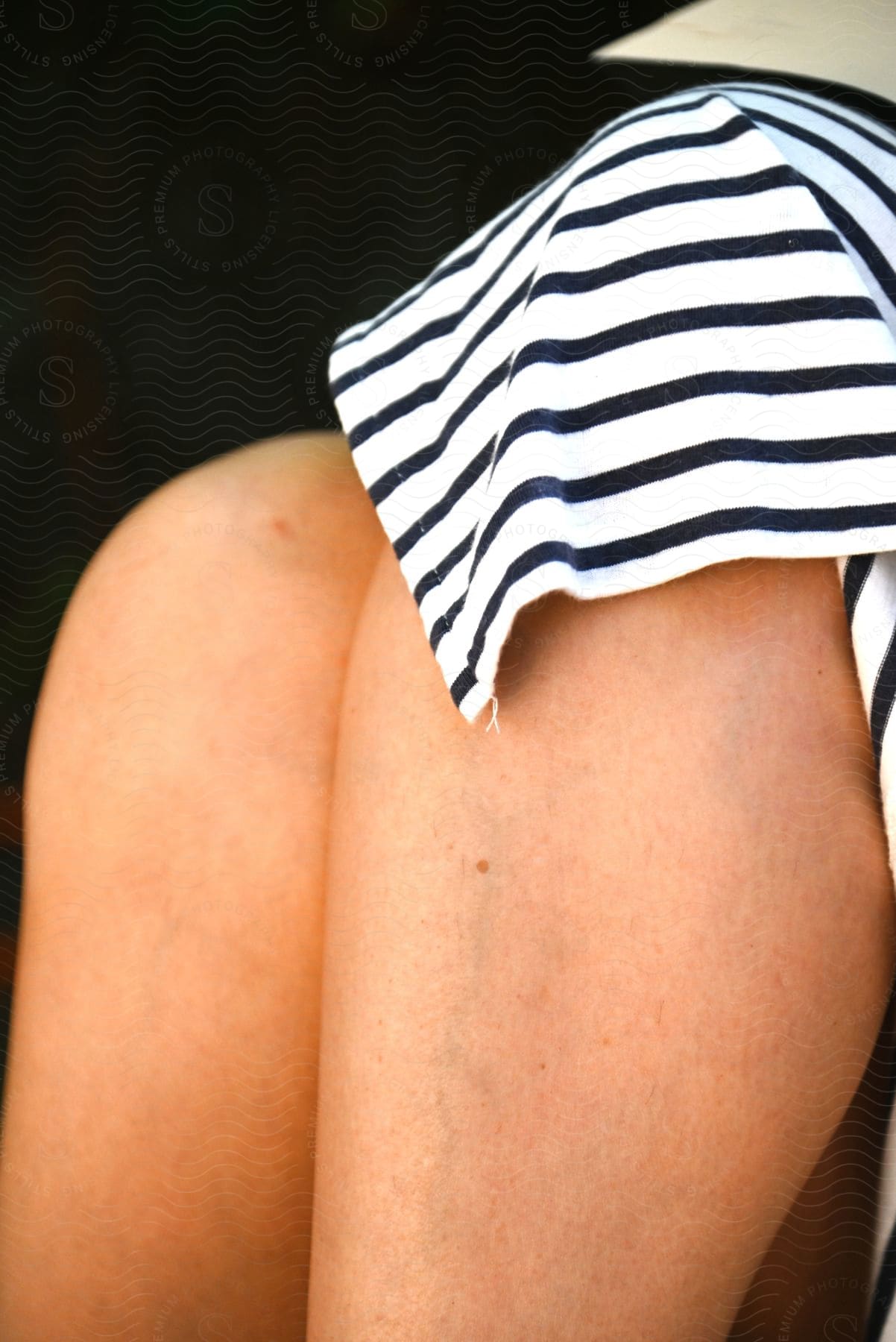 Stock photo of close-up of a woman's crossed legs in a striped skirt