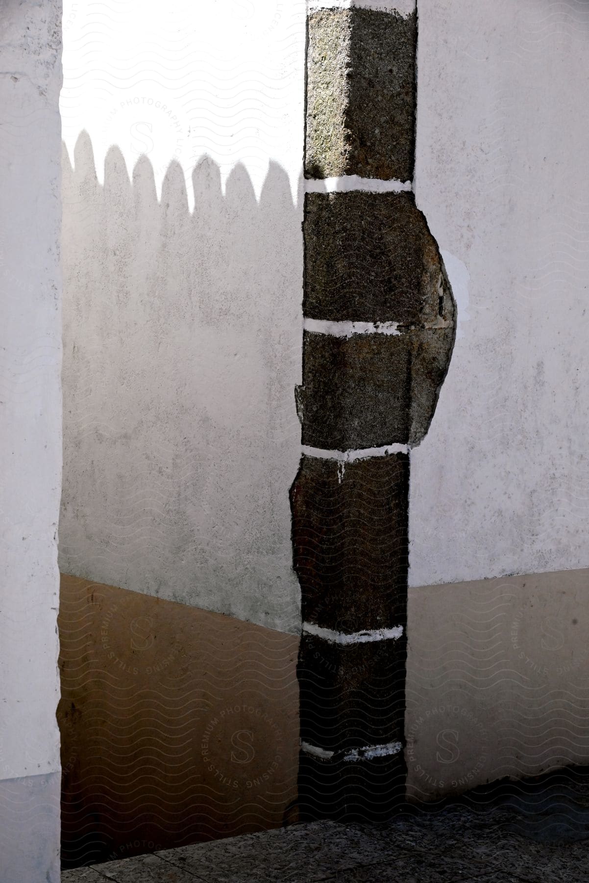 A white wall with a brown corner and a detailed roof shadow