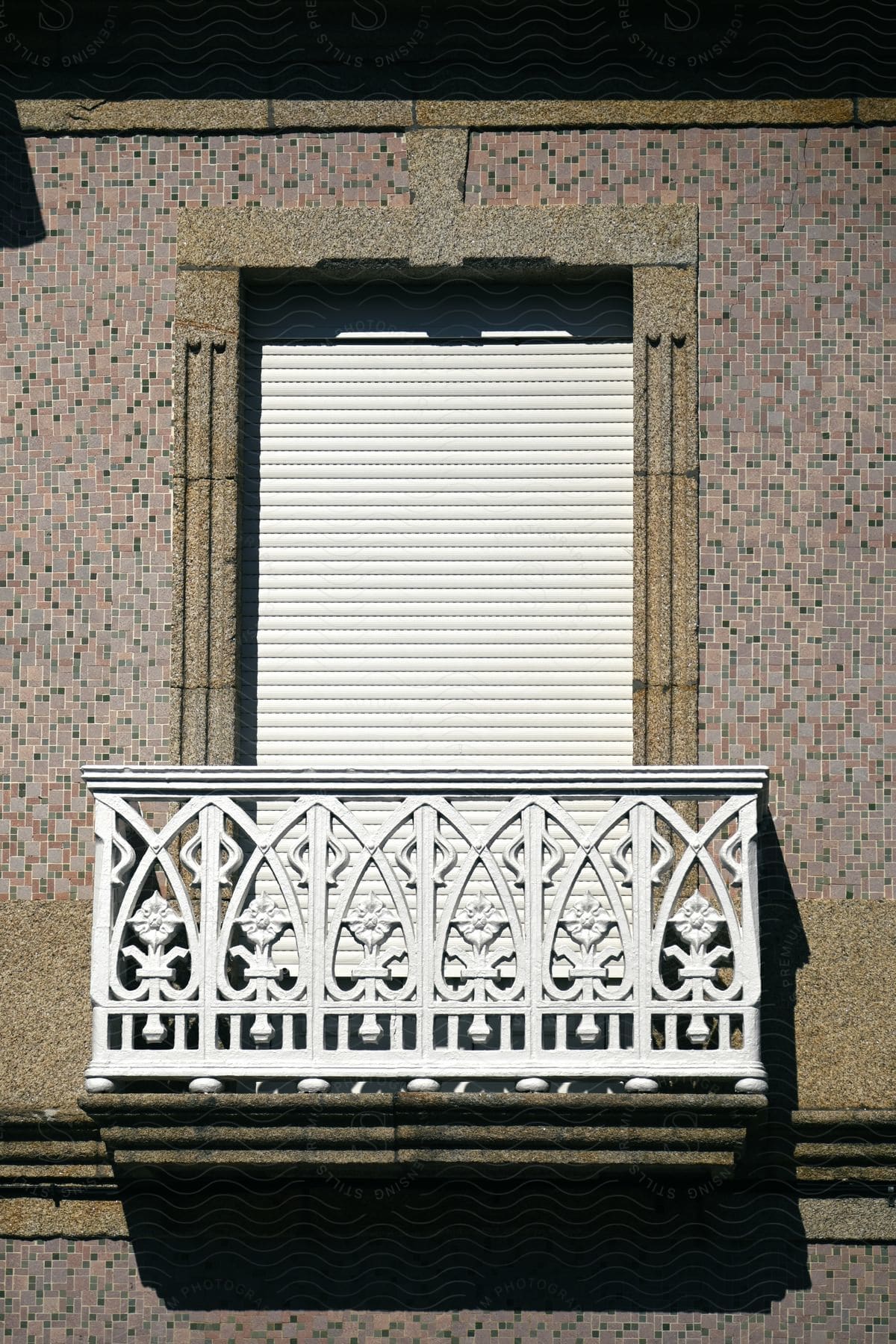 A shuttered window with white painted wrought iron balcony.