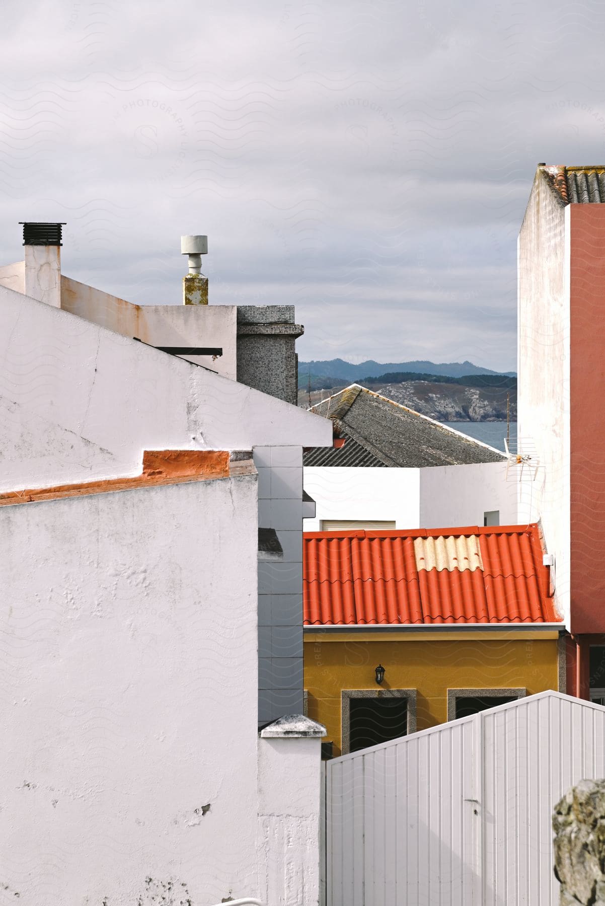 Exterior architecture of a residential neighborhood with white walls, colorful roofs and the sea on the horizon