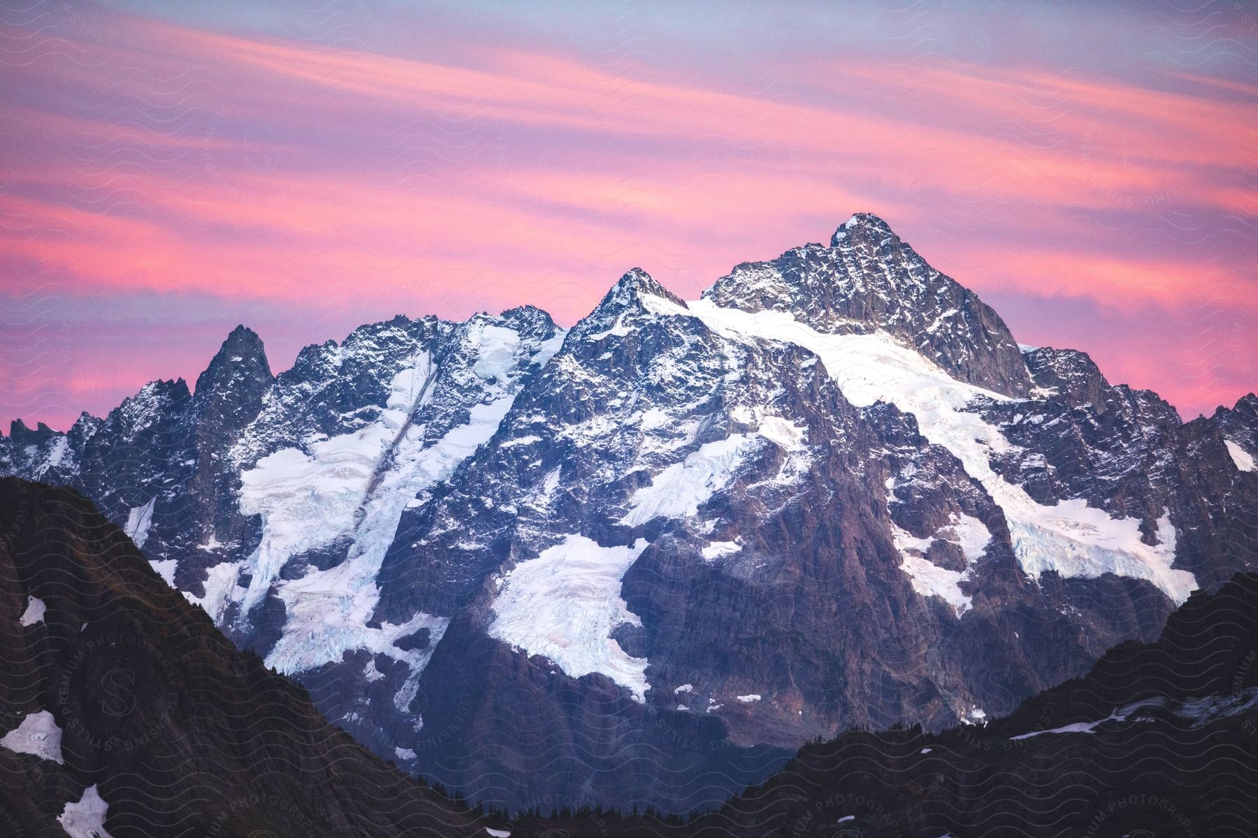 A majestic range of snow-capped mountains, framed by a colorful sunset sky.