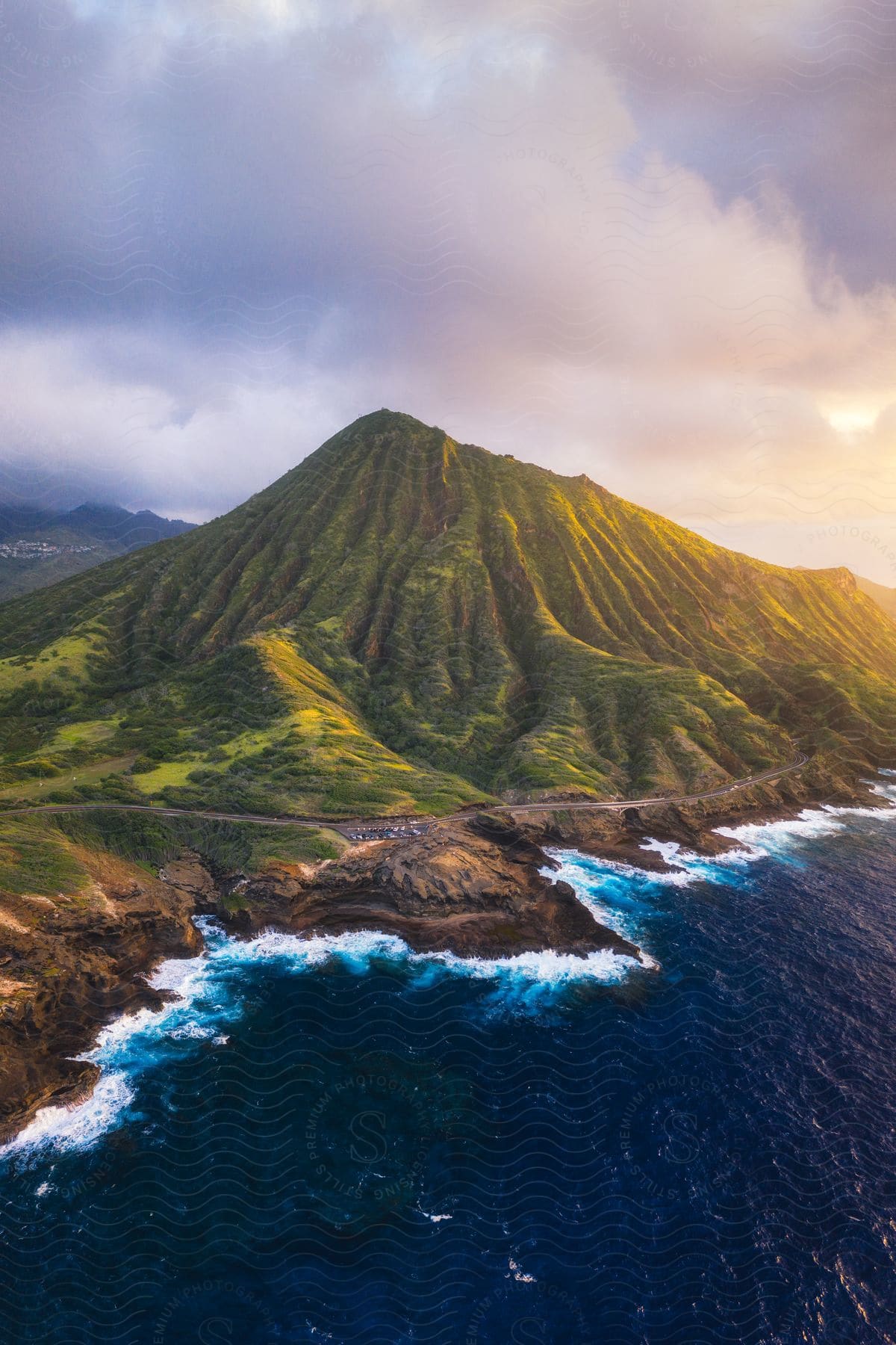 aerial view of a volcanic mountain with a lush green crater nestled beside a blue ocean.