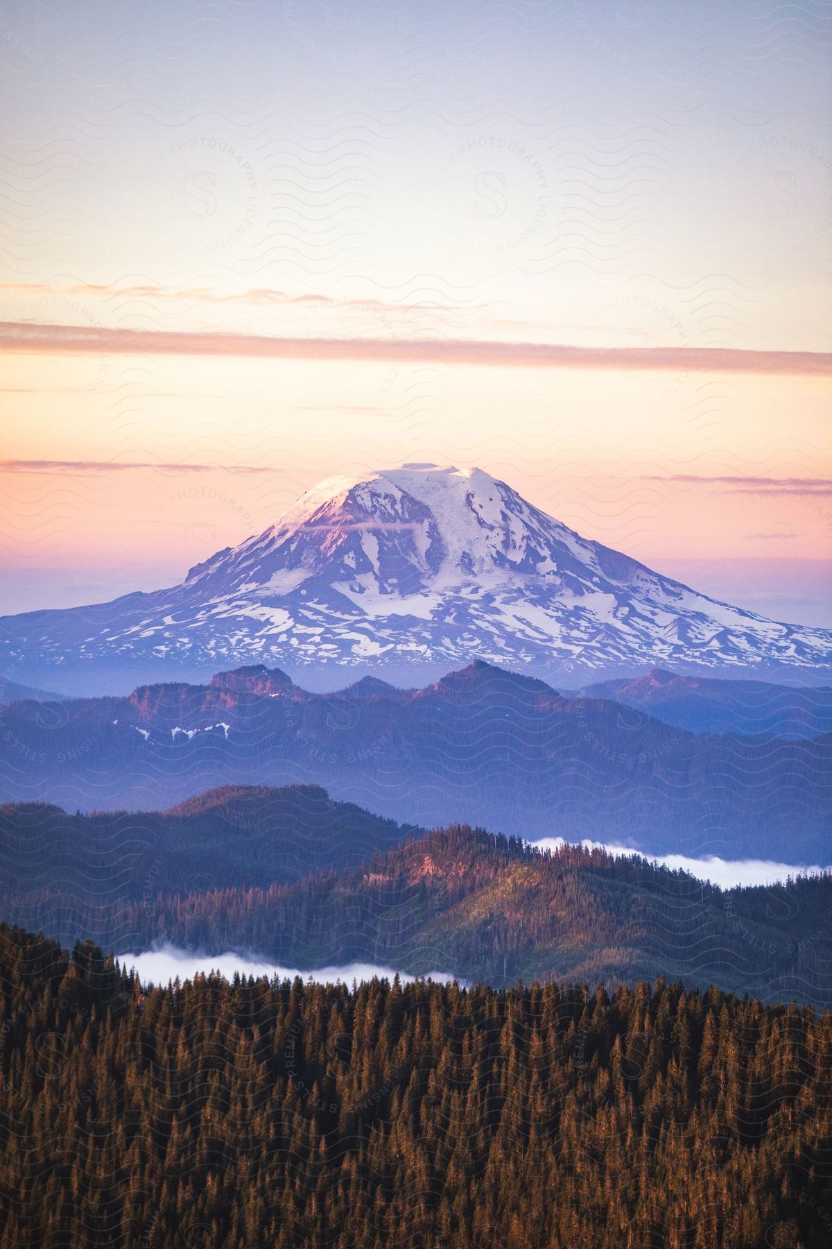 Forested mountains with a snow covered mountain in the distance