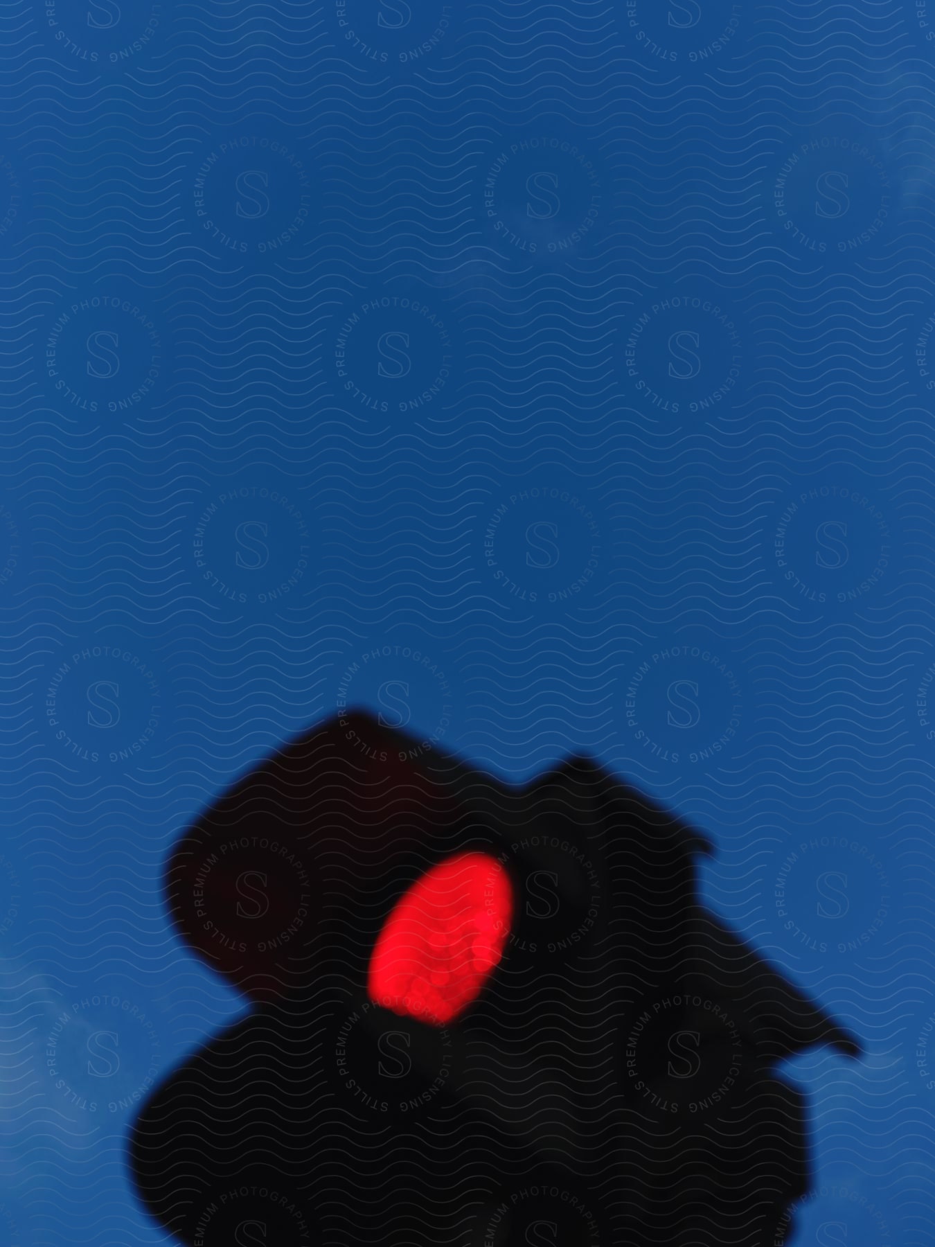 Abstract crop of red traffic light against blue night sky