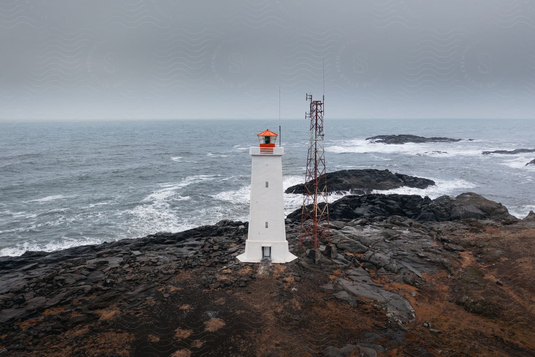 A lighthouse with radio tower on a rocky coast