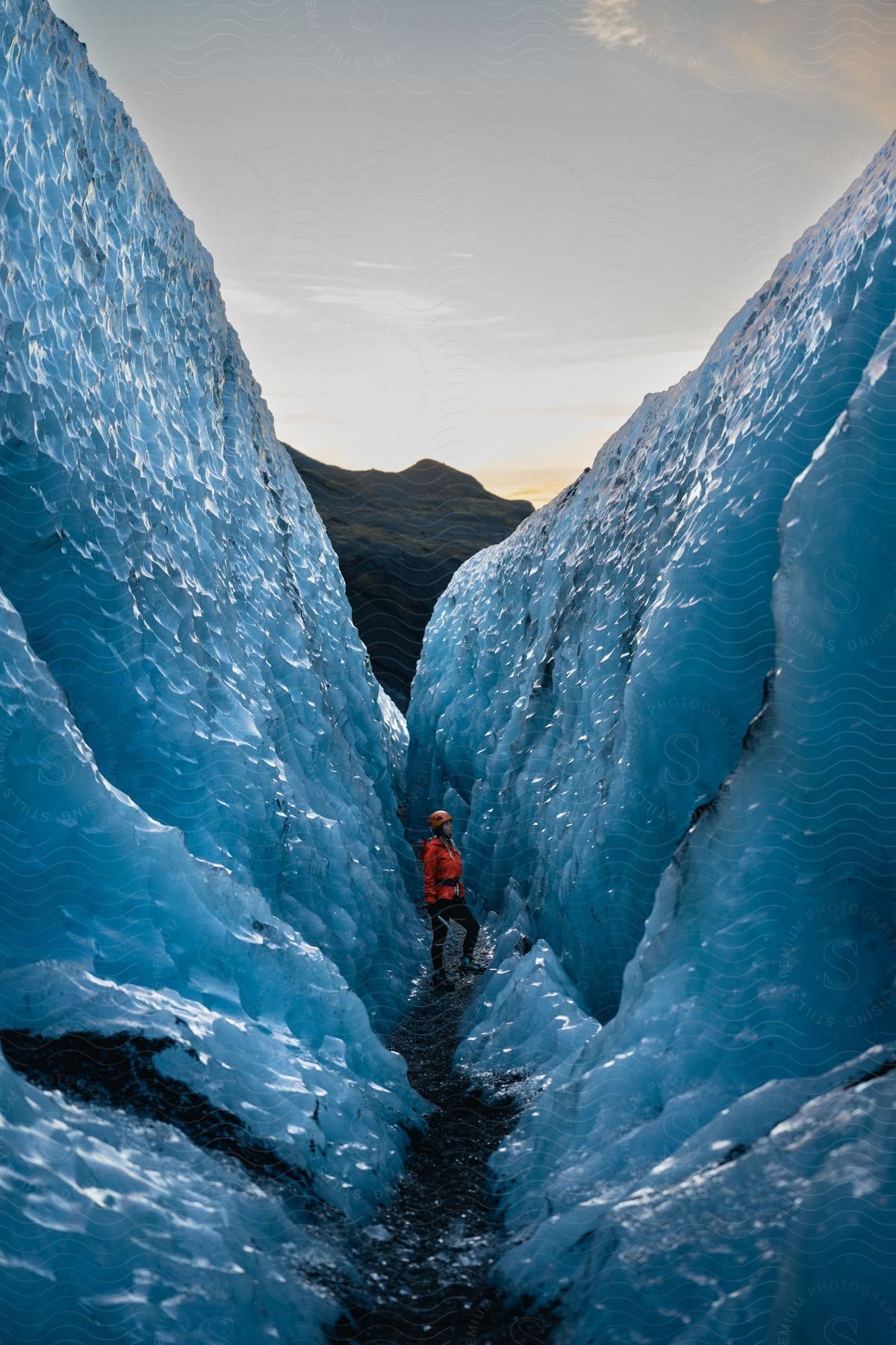 A person stands between two ice caps during a hike in the daytime.