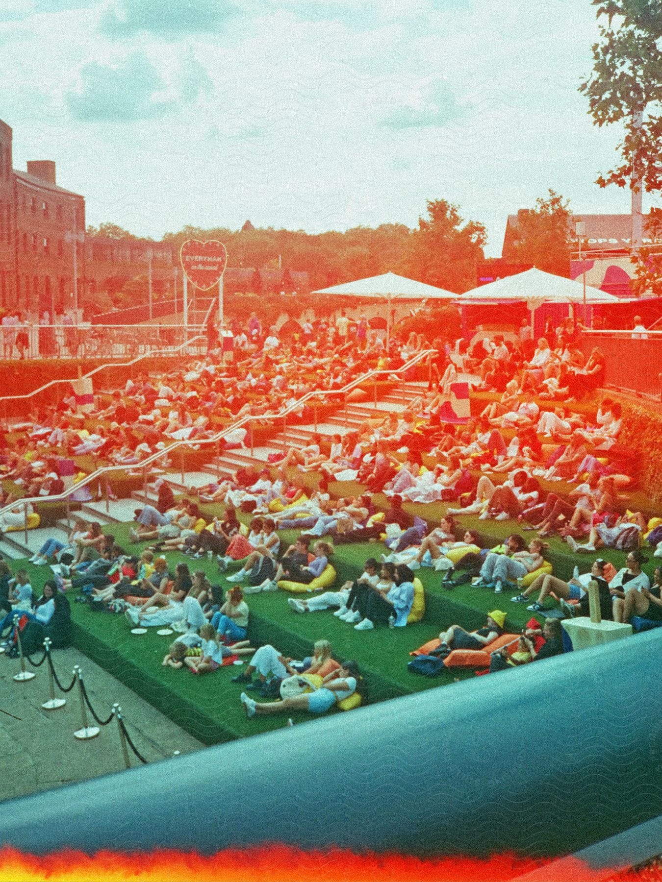 Crowd of people in bleachers sitting in an open-air cinema.