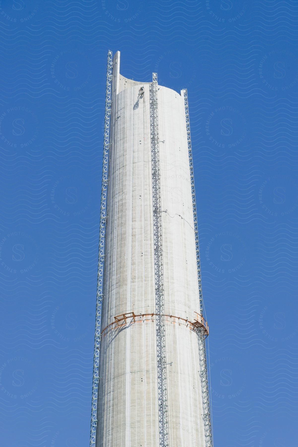 An industrial cooling tower with a man cleaning the outside.