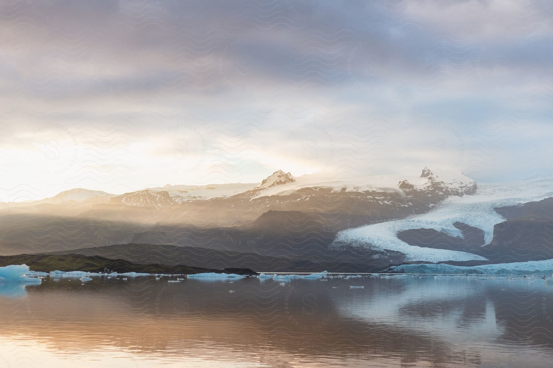 An icy lake is seen at sunrise, with ice covering part of the river bank.