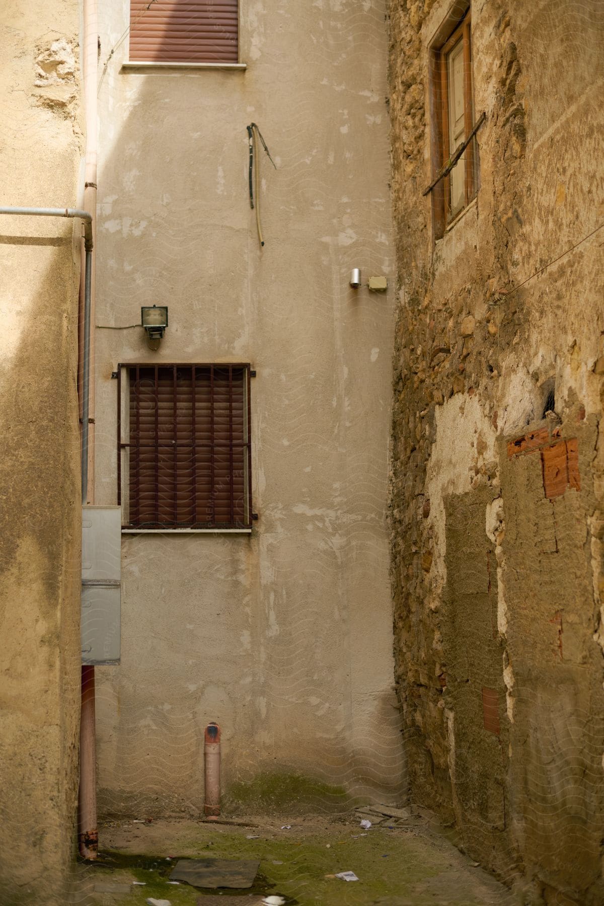 The alley and corner of a few buildings that are in a state of neglect and rusty.