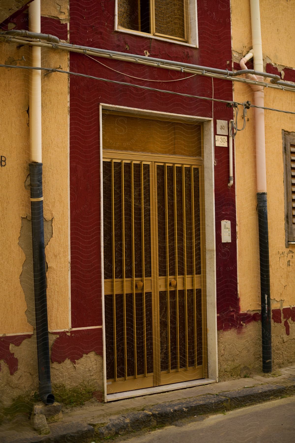 Metal door with slats centered on a red and yellow building